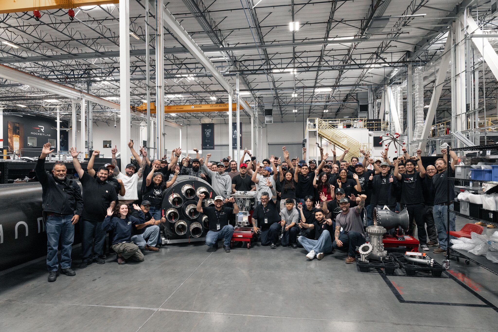Rocket Lab team members pose around the 1,000th 3D-printed Rutherford engine at the Long Beach facility, marking a production milestone